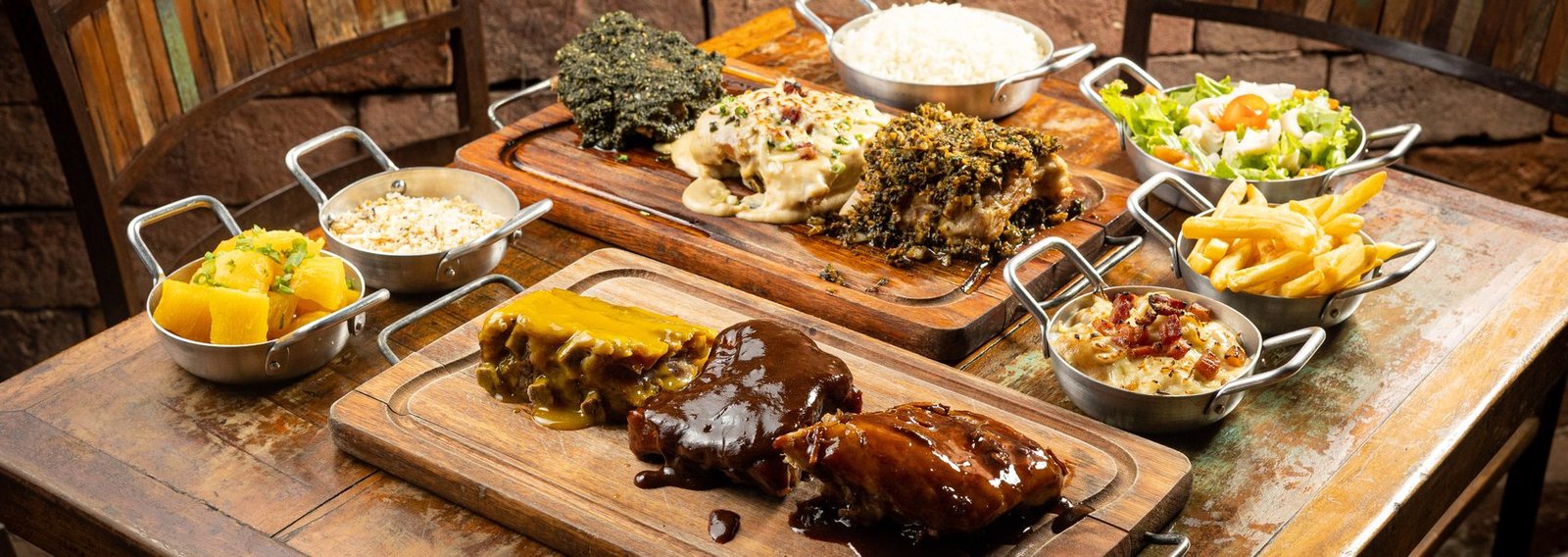 Mesa posta com tábuas de costela, acompanhamentos e cadeiras para o grupo